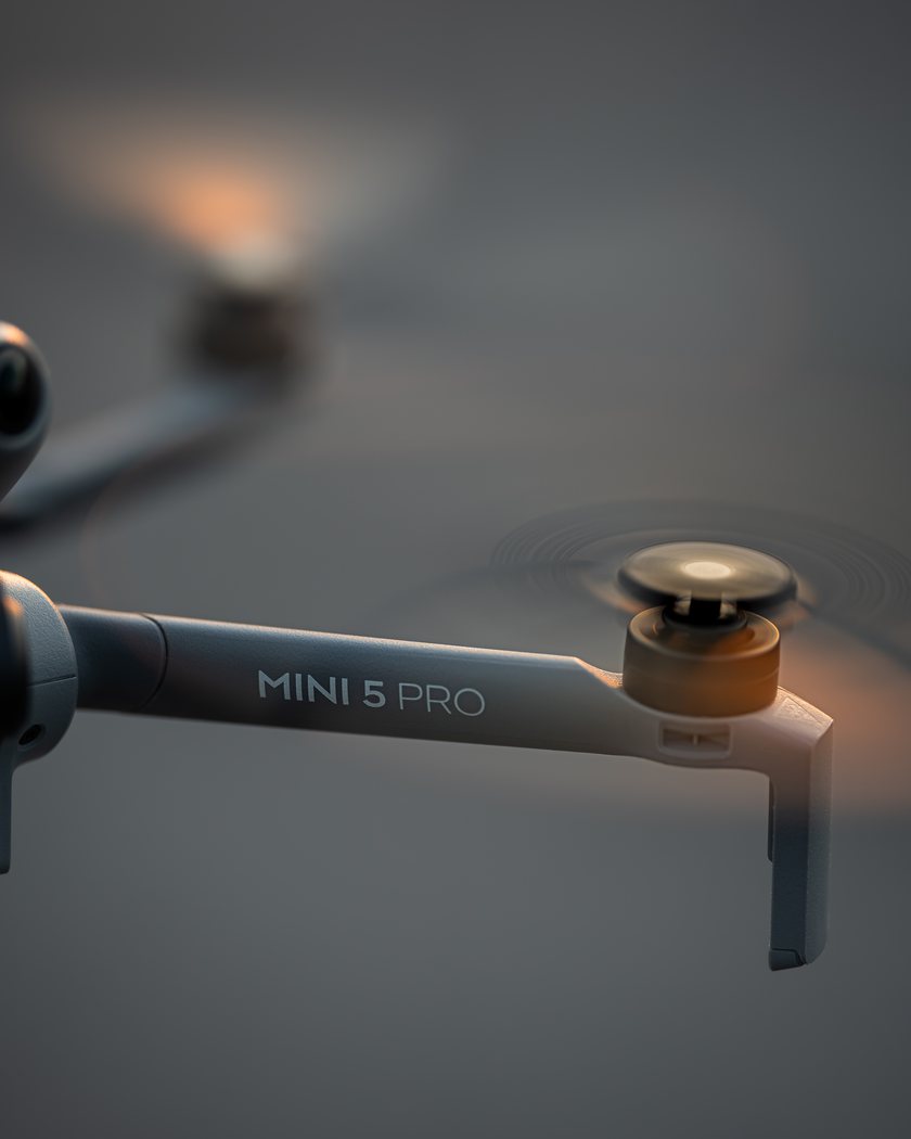DJI Mini 5 Pro drone hovering at golden hour, close detail of the airframe arm and rotor
