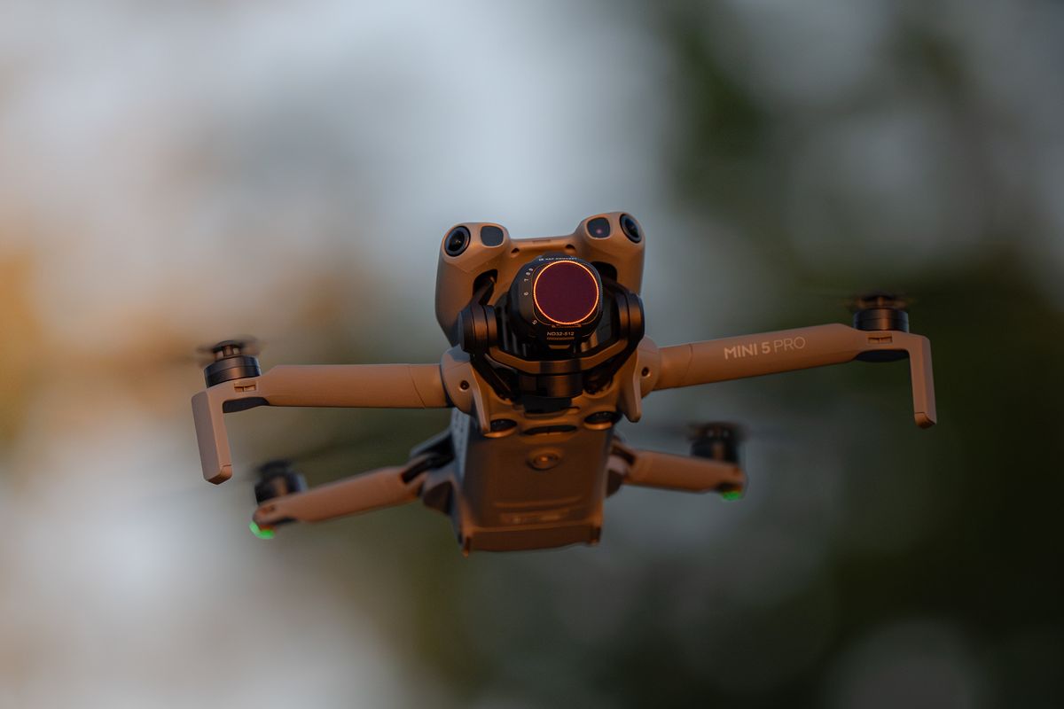 Drone hovering at dusk with obstacle sensors and navigation lights visible