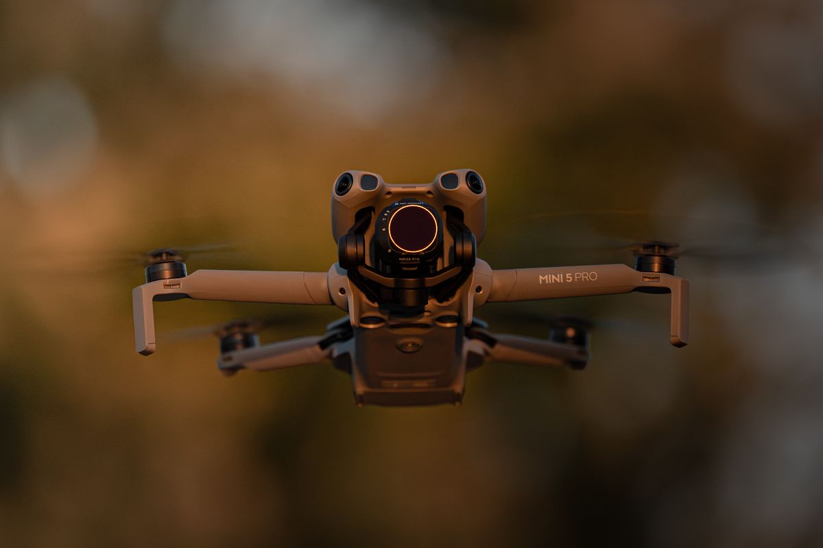 DJI Mini 5 Pro drone hovering at golden hour against warm Ontario treeline